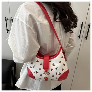 Detail of white cherry print tote bag with red shoulder strap and gold metallic buckle