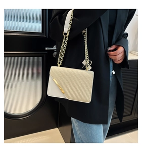 Detail of cream shoulder bag showing textured weave, smooth leather, and gold metal trim