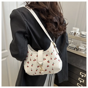 Detail of white cherry print hobo bag with gold metal buckle on a shoulder strap