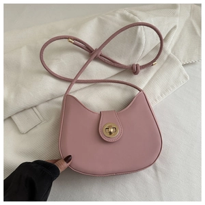 Dettaglio della borsa a mezzaluna rosa con chiusura a scatto dorata su maglia bianca