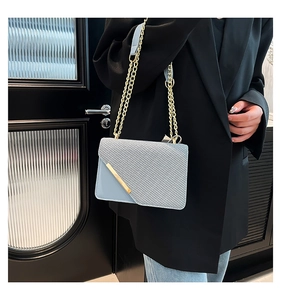 Gros plan du sac bandoulière bleu clair avec chaîne dorée et texture tissée