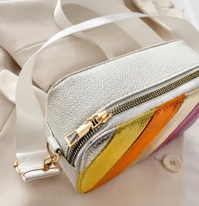 Detail shot of the smooth gold metal zipper on white pebble leather crossbody bag