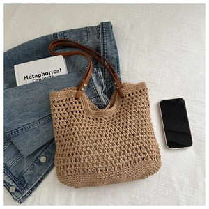 Detail of woven beach tote showing leather handles and rivet accents on khaki knit texture