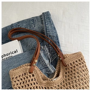 Detail view of hollow crochet tote bag with brown leather handles and metal rivets