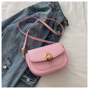 Détail du sac selle en similicuir rose avec boucle dorée sur une veste en jean