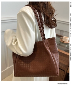 Détail d'un cabas marron avec texture gaufrée et bandoulière tressée porté par un mannequin