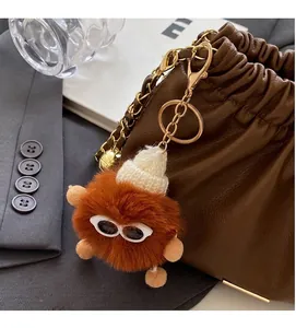 Brown plush charm with white knit hat and sunglasses attached to a stylish bucket bag