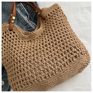 Close-up of hollow crochet woven tote bag with premium leather handles and metal rivets