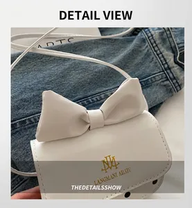 Close-up of white mini crossbody bag with large bow detail and gold logo on denim fabric