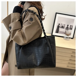 Dettaglio borsa shopper nera in pelle testurizzata con tracolla intrecciata alla moda