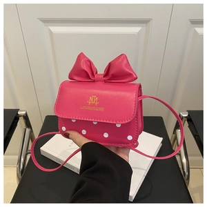Detailed view of pink mini crossbody bag with a large bow and white polka dot patterns