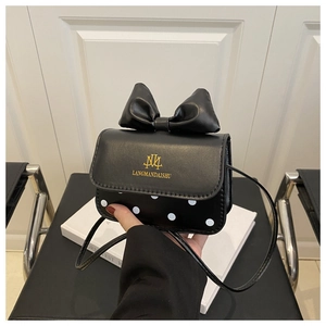 Detail view of mini black crossbody bag with large bow and white polka dots pattern