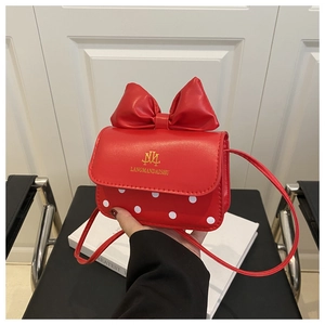 Detail of red mini crossbody bag featuring white polka dots and a large 3D bow accent