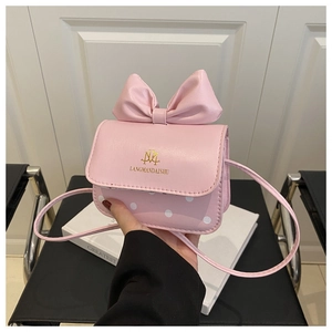 Detailed close-up of a pink mini crossbody bag featuring a large bow and white polka dots
