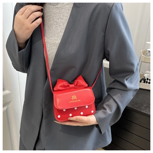 Close-up of mini red crossbody bag with bow detail and white polka dots on model