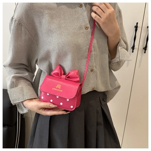 Detail of pink mini crossbody bag with a 3D bow and white polka dots on the front