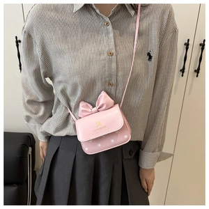 Close-up of pink bow and white polka dot pattern on a mini square crossbody bag