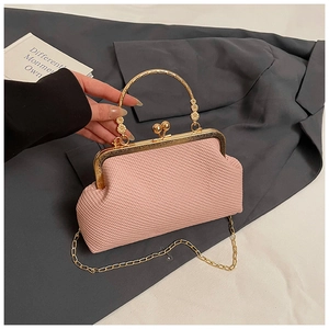 Détail d'un sac tressé rose avec poignée dorée posé sur une veste de costume