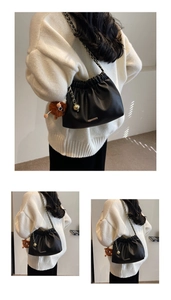 Detail of black pleated bucket bag with gold chain strap and fuzzy monster charm