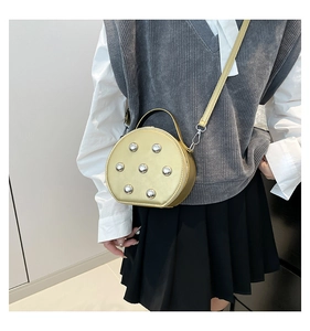 Detalle del bolso de media luna dorado con remaches metálicos y textura de piel