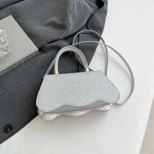 Detail of silver glitter handbag featuring a wave-shaped base and gold hardware accents