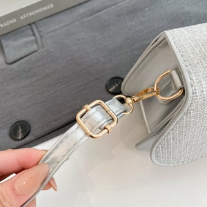 Detail of glitter handbag showing golden metallic hardware and adjustable strap attachment
