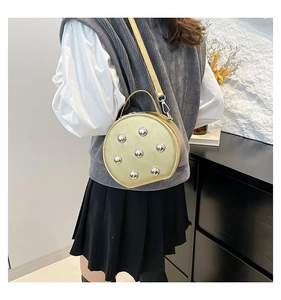 Detail of round crossbody bag featuring silver stud embellishments and slim shoulder strap