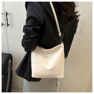 Détail du sac seau en cuir PU blanc cassé sur mannequin pour un look décontracté chic