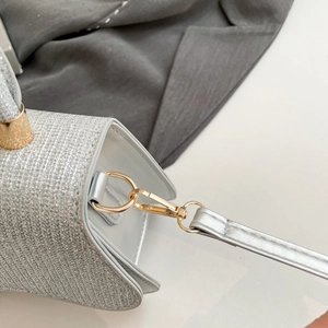 Detail of silver glitter handbag featuring gold metal hardware and detachable strap