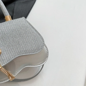 Close-up of shimmering silver rhinestone handbag with elegant wave shape and gold hardware