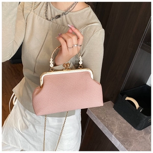 Pink woven bag with floral handle and gold frame, shown worn as an elegant shoulder bag
