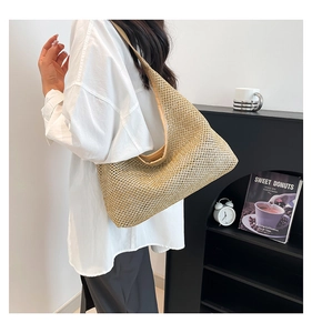 Detail view of large woven tote bag in metallic gold finish shown on model's shoulder