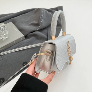 Detail of silver glitter handbag with gold metal hardware and textured side panels