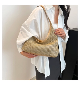 Macro detail of crescent woven tote bag with brown leather trim and golden straw texture