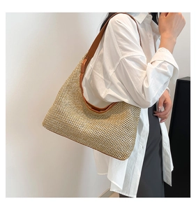 Detail of woven straw tote bag with brown faux leather trim and mesh texture patterns