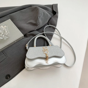 Detail of silver wavy handbag with shimmering texture and golden S-shaped metal logo