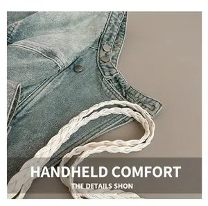 Macro detail of a light blue denim tote with white braided handle and metal buttons