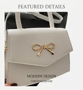 Close-up of white mini handbag with golden bow metal clasp and textured finish