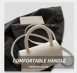 Detail of white mini handbag with golden bow accent and detachable shoulder strap