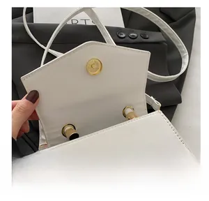 Detailed view of white mini crossbody bag featuring a golden magnetic snap closure