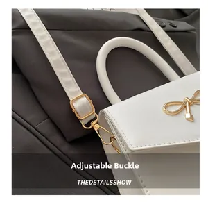 Macro detail of the adjustable gold buckle and white leather strap of the stylish handbag