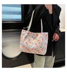 Detail of floral tote bag showing textured fabric, woven handles and metal brand plate