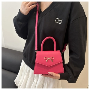 Detailed shot of hot pink square bag featuring a gold bow buckle and matte PU leather