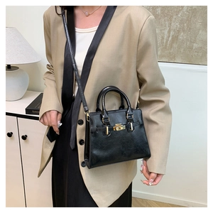 Detail of black Kelly handbag with golden turn-lock and detachable shoulder strap