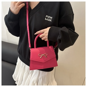 Detail of rose red mini crossbody bag with golden bow and V-shaped flap cover