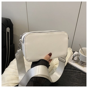 Detail view of white PU leather crossbody camera bag with wide nylon strap and silver zipper