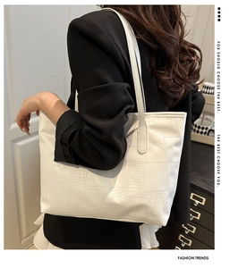 Detail of white tote bag featuring geometric crocodile texture patchwork and slim straps