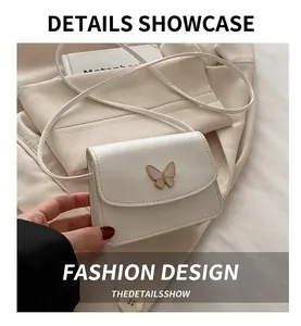 Close-up of a white mini crossbody bag with a golden butterfly clasp and neat stitching