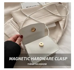 Detail of white mini crossbody bag showing golden magnetic clasp and inner compartment