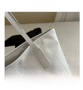 Close-up of white tote bag showing detailed faux crocodile texture and sturdy stitching